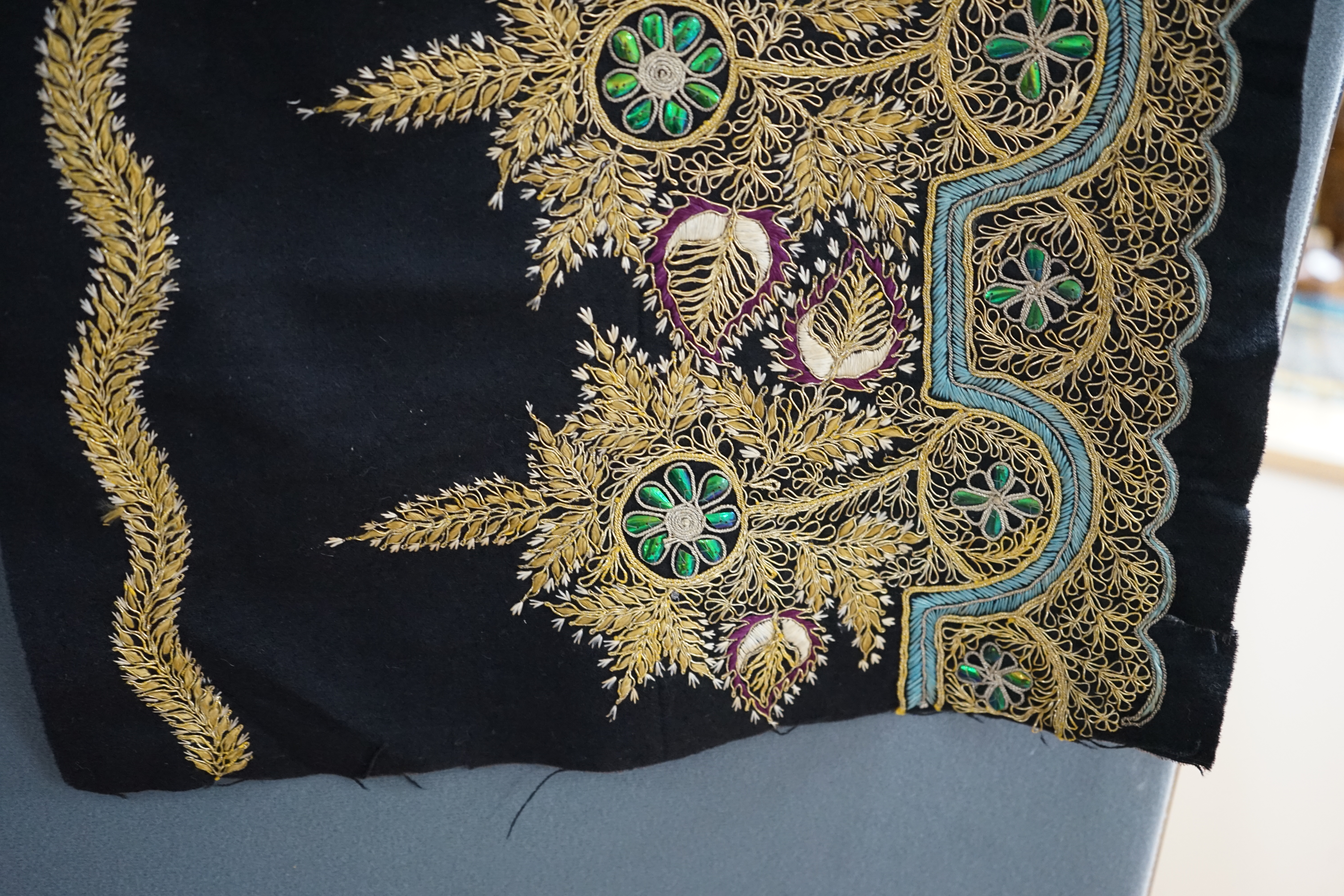 An Indian black felt panel embroidered with mostly gold thread, some coloured silks and beetle wing ornamentation, possibly a border to a larger panel, 256cm long. Condition - good